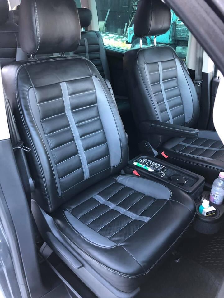 Tapicerowane na nowo fotele samochodowe, czarno-szara skóra z przeszyciami, widoczny fragment wnętrza pojazdu.