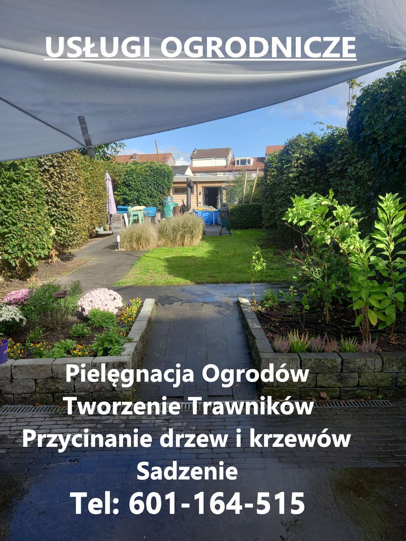 Ogród z zadbanym trawnikiem, rabatami kwiatowymi w kamiennych obrzeżach i żywopłotem, widok z perspektywy ścieżki, nad ogrodem rozpięta biała płachta cieniująca.