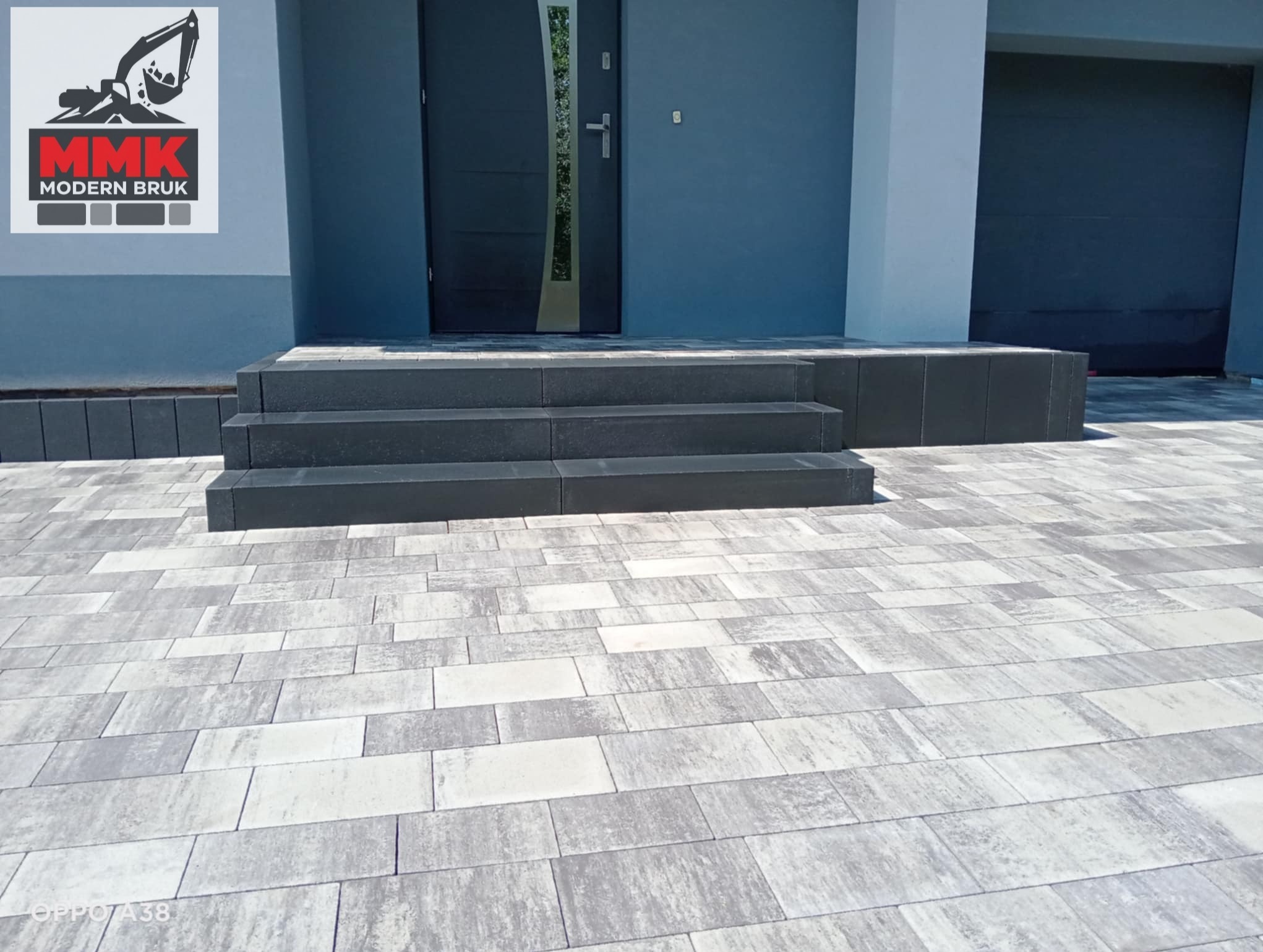 Nowoczesne podejście do domu w Strzyżowicach, z eleganckimi schodami i chodnikiem z kostki brukowej w odcieniach szarości. Perfekcyjne wykończenie i dbałość o detale.