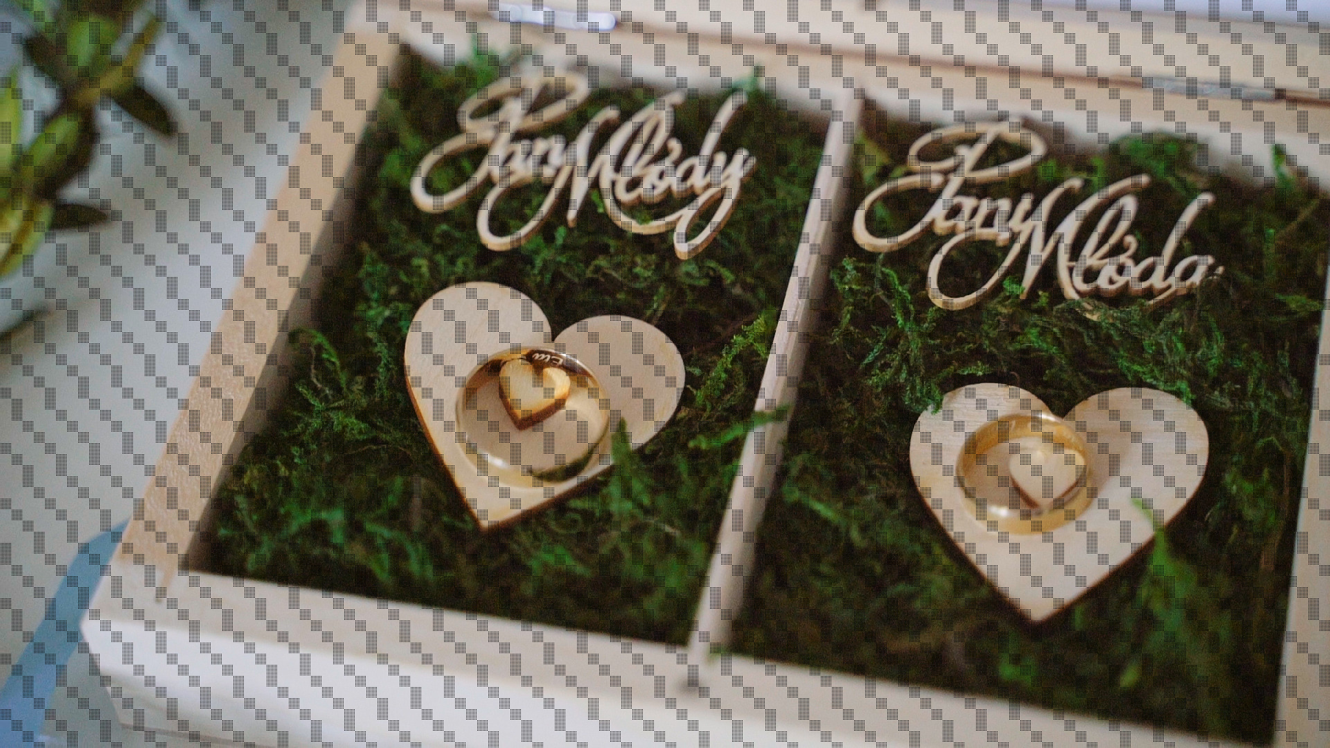 Drewniane pudełko z mchem, w którym umieszczono obrączki ślubne w drewnianych sercach, nad nimi napisy 'Pan Młody' i 'Pani Młoda' wykonane ozdobną czcionką.