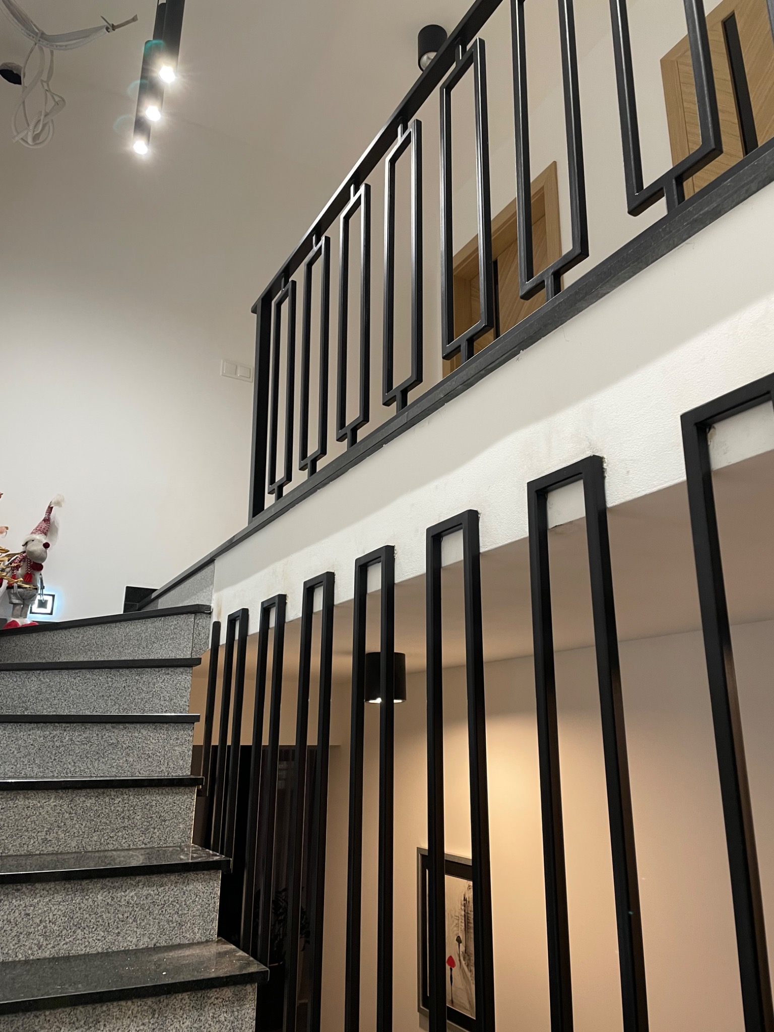 Nowoczesna balustrada z czarnych profili stalowych w Sosnowcu, widok z dołu na schody z szarego kamienia i górną część balustrady, minimalistyczny design.