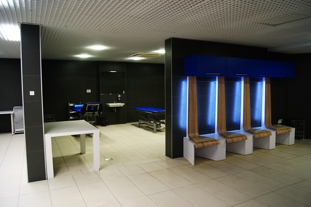 Wnętrze lokalu usługowego w Warszawie z nowoczesnymi, podświetlanymi krzesłami w poczekalni i sprzętem do zabiegów w tle.