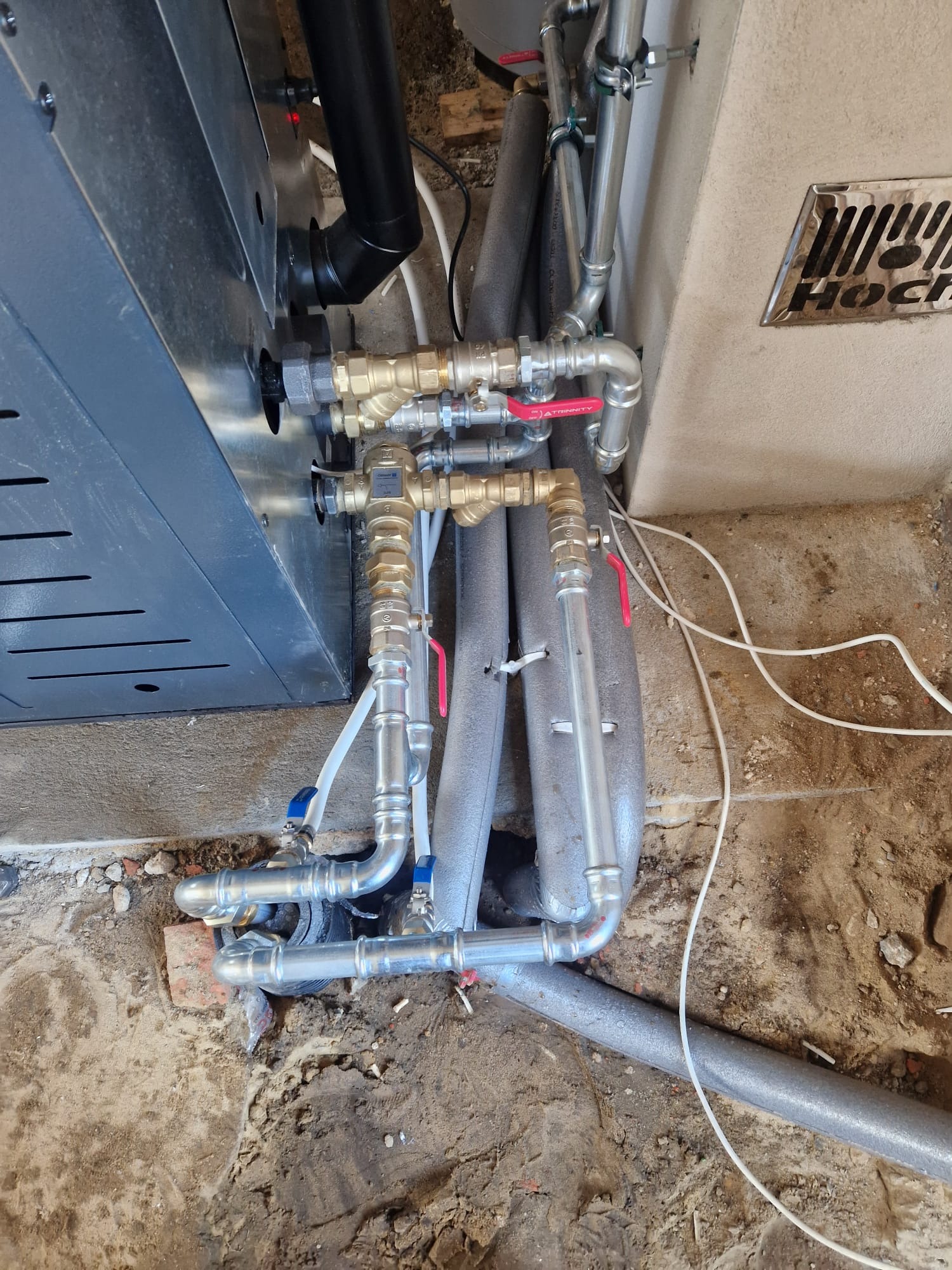 Szczegółowe ujęcie instalacji CO z rurami miedzianymi i zaworami, izolowane przewody, piec gazowy, elementy montażowe. Widok na przyłącza w nowym budynku.