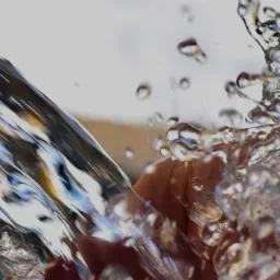 Strumień czystej wody wylatujący z rury podczas wiercenia studni, z widocznymi kroplami i rozbryzgami.