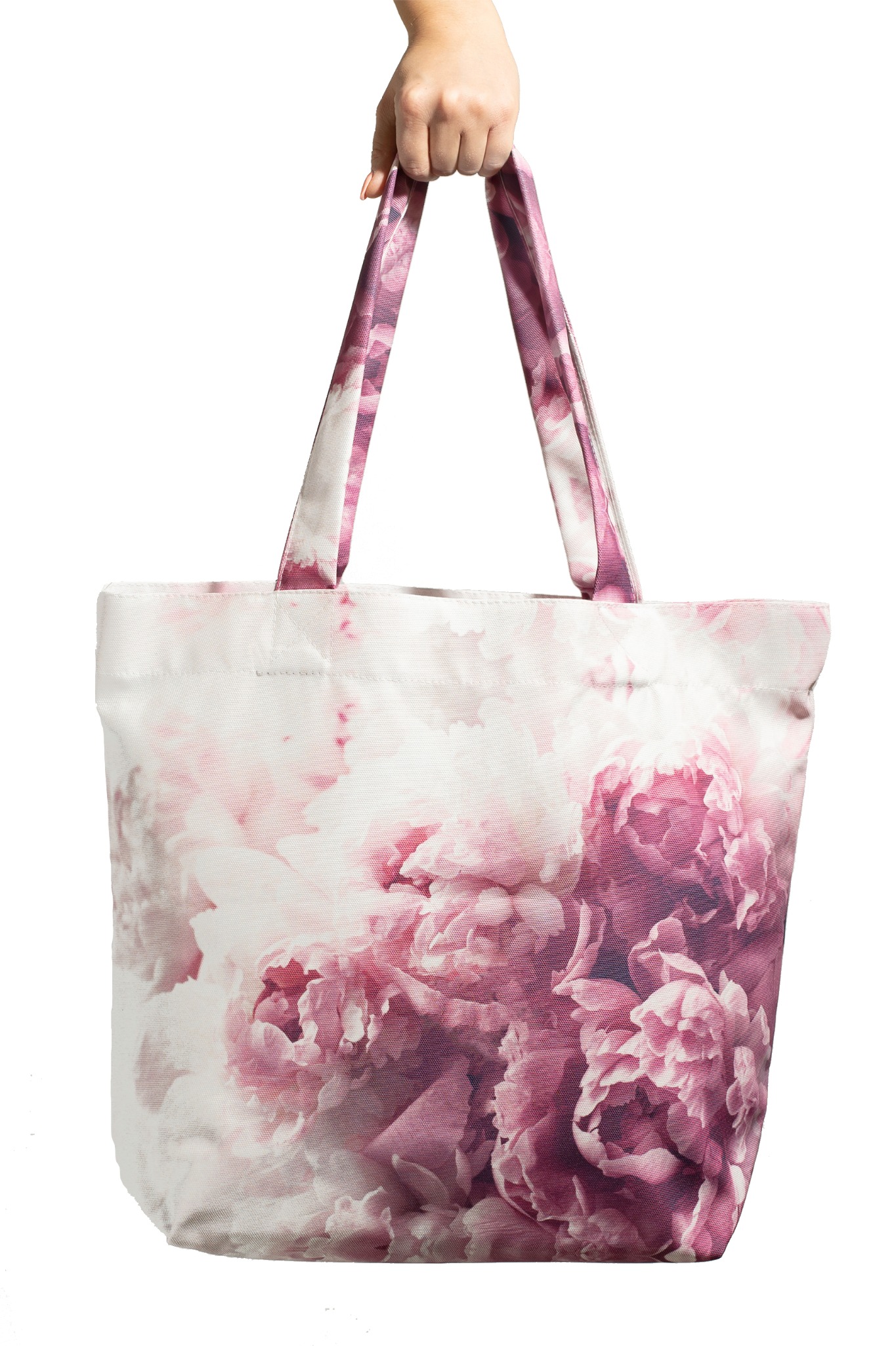 Torba na zakupy z tkaniny z motywem różowych piwonii, trzymana w dłoni na białym tle.