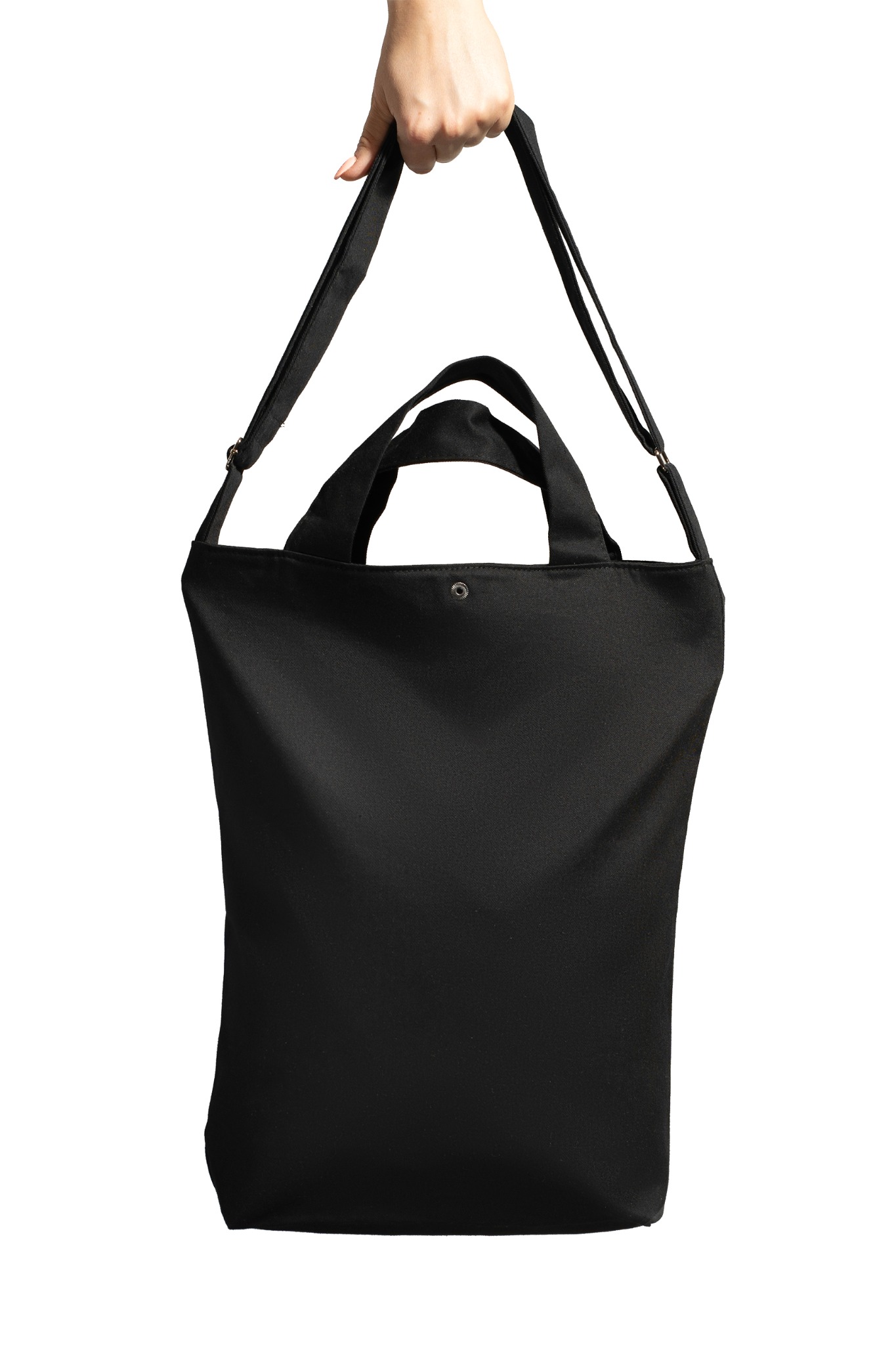 Czarna torba materiałowa z krótkimi uchwytami i długim paskiem na ramię, trzymana w dłoni na białym tle.