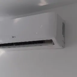 Biała jednostka klimatyzacji Midea zamontowana na białej ścianie, widoczny wyświetlacz z cyfrą '2' i kratka wylotowa.