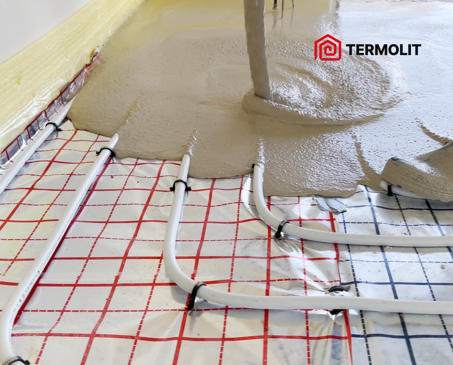 Wylewka anhydrytowa rozprowadzana na instalacji ogrzewania podłogowego z widocznym logo Termolit w prawym górnym rogu.