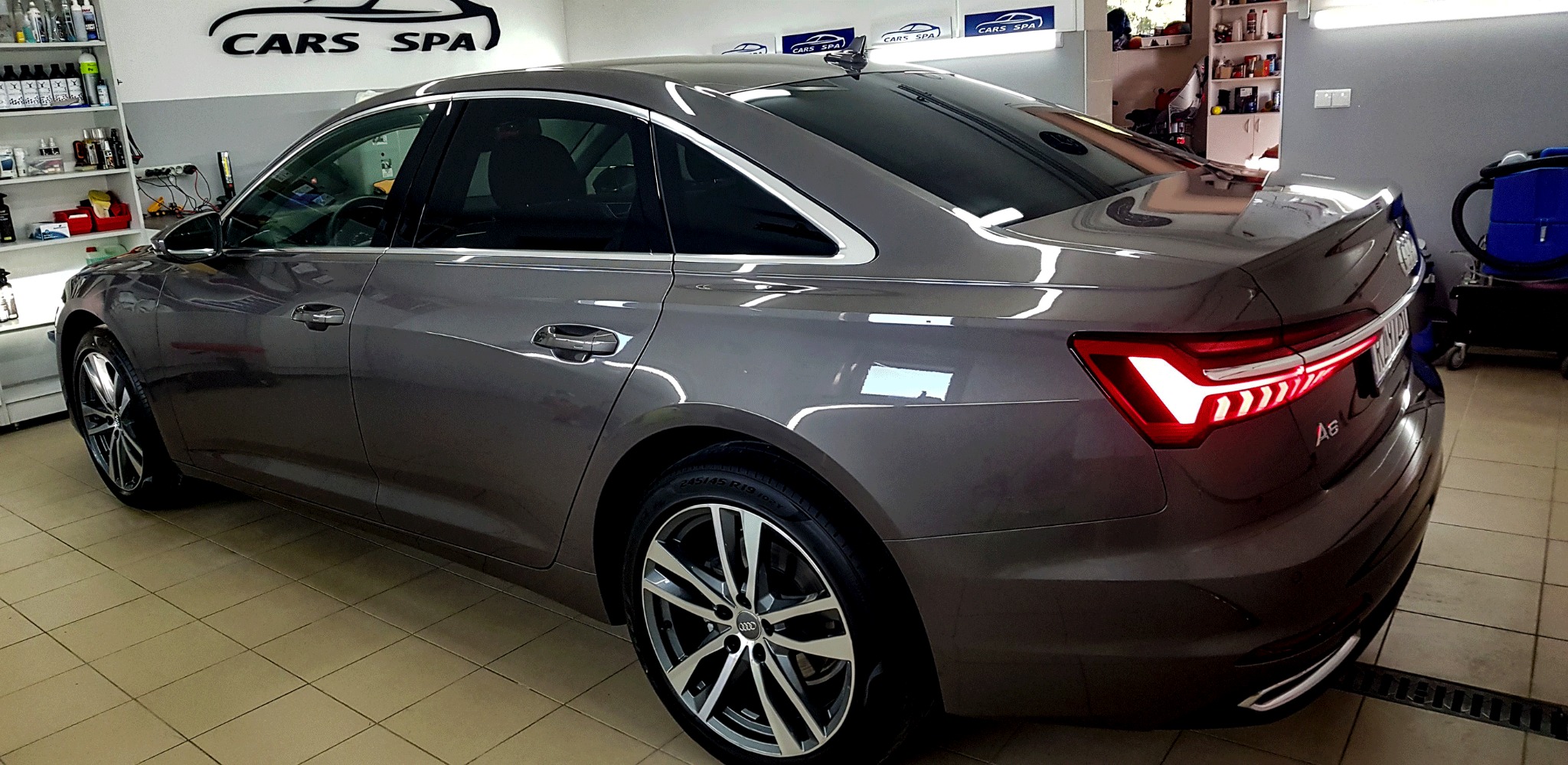 Błyszczący, szary samochód Audi A6 po usłudze detailingu w Cars Spa w miejscowości Wysoka, widoczny z boku i tyłu, z włączonymi światłami stopu.