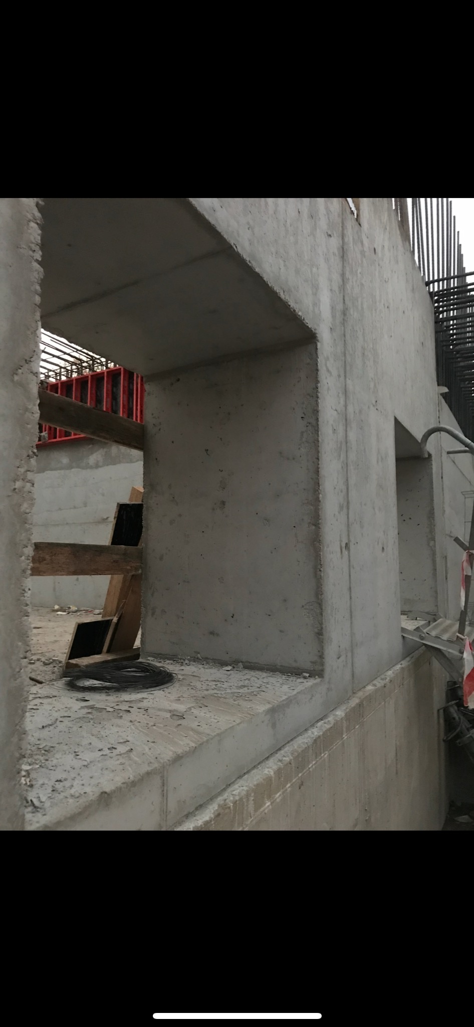 Surowa betonowa konstrukcja w trakcie budowy z widocznym zbrojeniem i deskowaniem w tle.