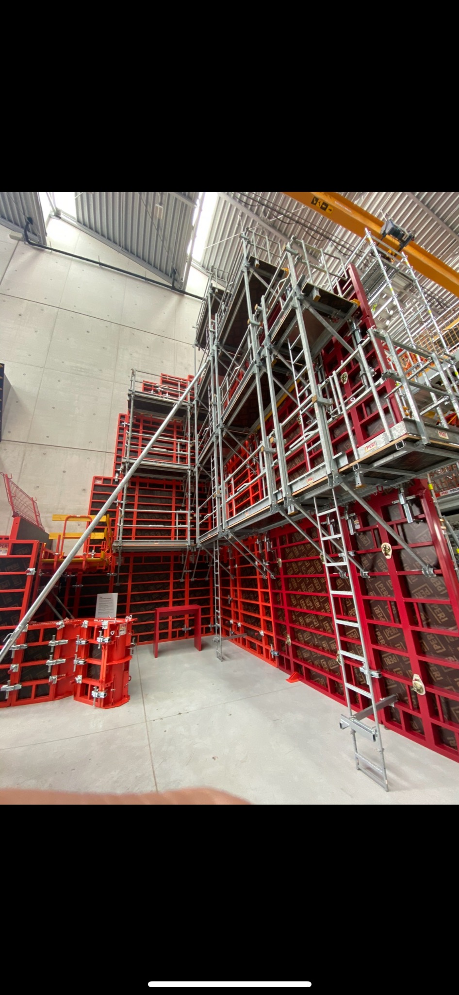 Skomplikowany system szalunków z rusztowaniami, przygotowany do wylewania betonu, widoczny w przestronnym wnętrzu hali w Warszawie.