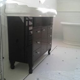 marek witkowski - Czarna szafka łazienkowa z umywalką w stylu retro, na tle białej wanny wolnostojącej i grzejnika drabinkowego.