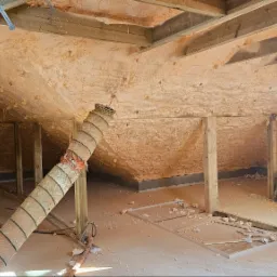 Poddasze w Starym Kurowie po ociepleniu pianką PUR, widoczna struktura piany na skośnych ścianach i suficie, przewód wentylacyjny oraz rusztowanie.