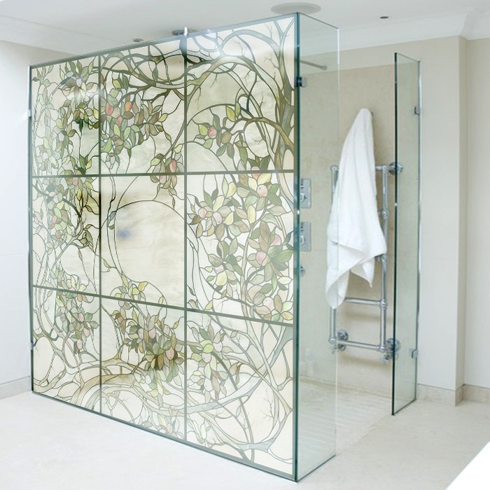 Szklana kabina prysznicowa z dekoracyjnym motywem roślinnym, podzielona na kwadratowe panele, z widocznym chromowanym grzejnikiem na ręczniki w tle.