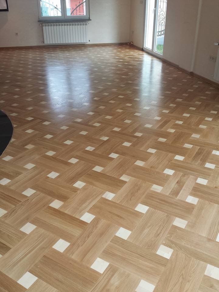 Parkiet ułożony w jodełkę z jasnymi wstawkami w Rzeszowie, po cyklinowaniu i lakierowaniu, widoczne okno i grzejnik.