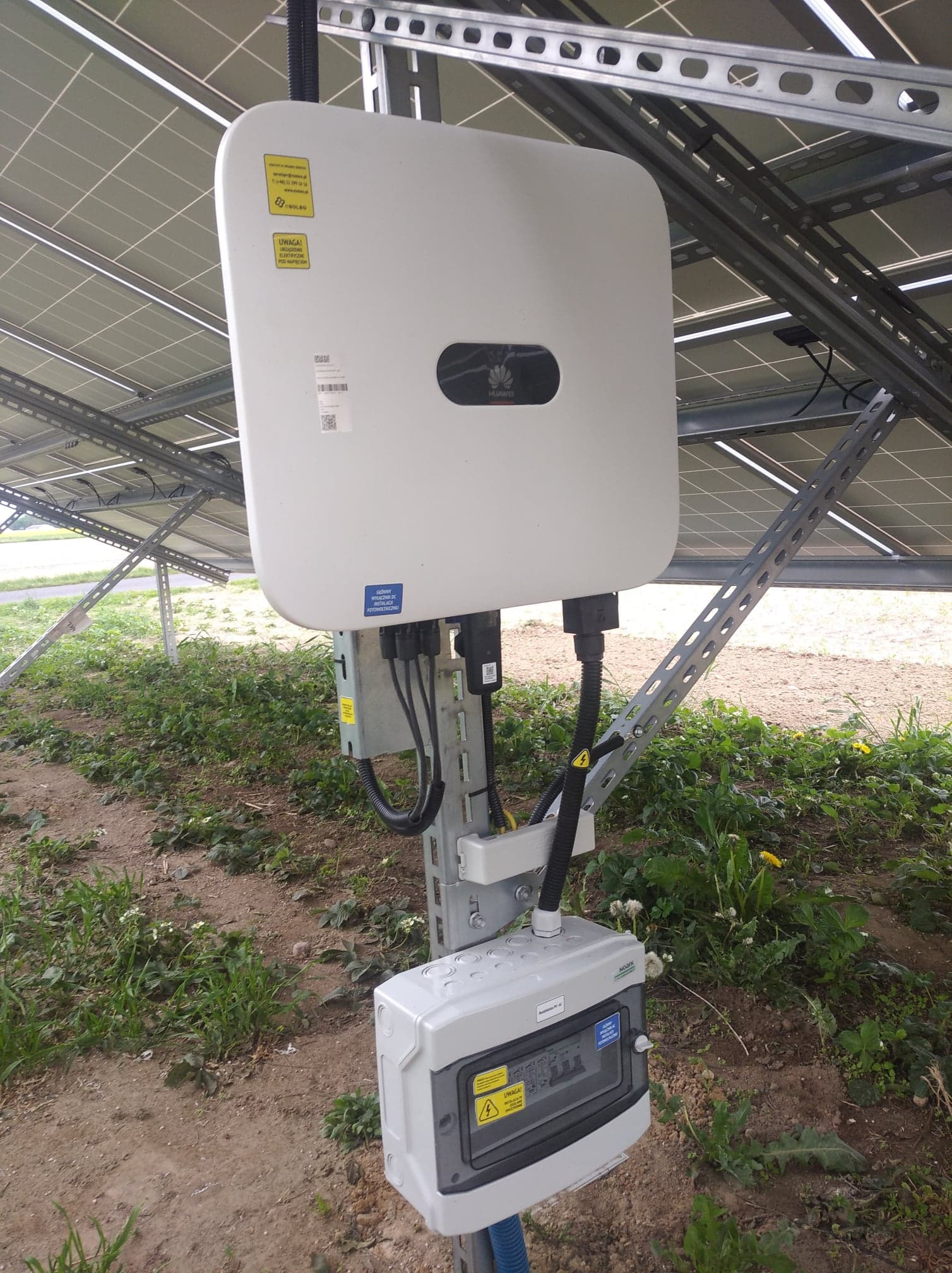 Falownik Huawei z rozdzielnią umieszczone pod panelami (instalacja na gruncie).