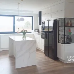 Białe klasyczne meble kuchenne wzbogacone niepowtarzalną witryną.