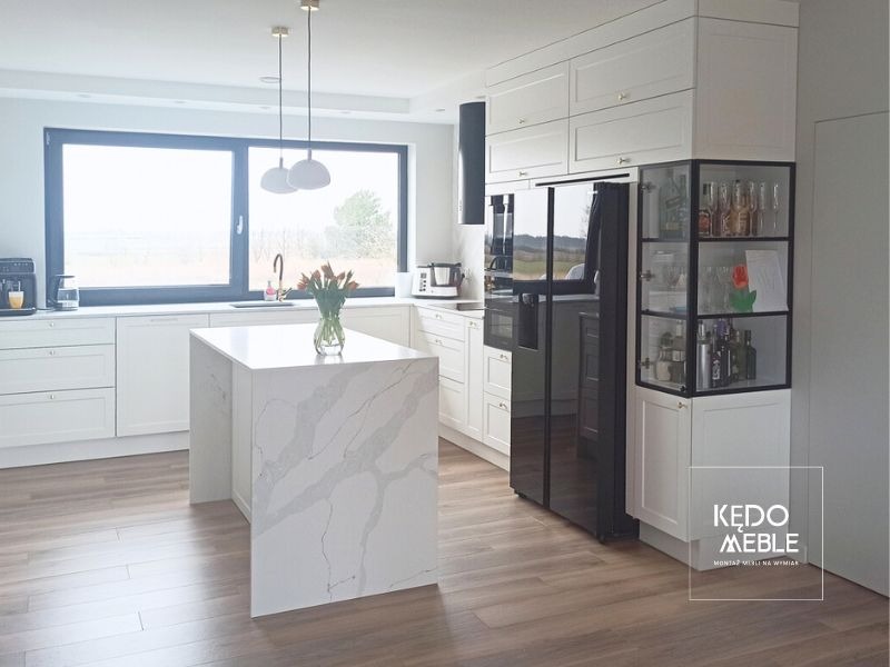 Białe klasyczne meble kuchenne wzbogacone niepowtarzalną witryną.