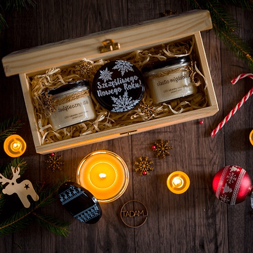 Świąteczna kompozycja: drewniana skrzynka z trzema świecami sojowymi o różnych zapachach (świąteczny stół, ciasto migdałowe, szczęśliwego nowego roku), ozdobiona sznurkiem jutowym i papierowym...