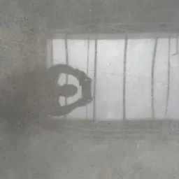 Szara, gładka posadzka z refleksami światła i cieniem osoby robiącej zdjęcie, widoczne delikatne wzory i tekstura betonu. Minimalistyczny efekt wizualny.