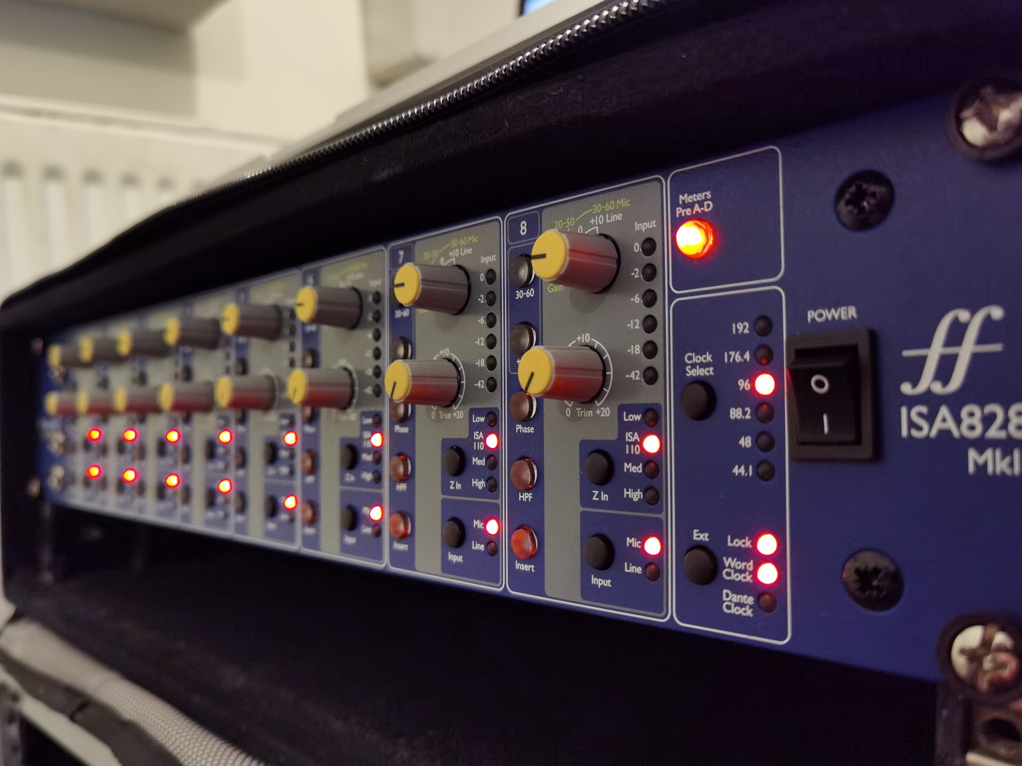 Sprzęt audio: przedwzmacniacz mikrofonowy Focusrite ISA828 MkII z włączonym zasilaniem i aktywnymi kanałami, widoczne pokrętła regulacji wzmocnienia i diody LED.