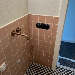 Fams bud - Łazienka po renowacji: różowe płytki ścienne, miedziana bateria, czarno-biała podłoga w szachownicę i czarne włączniki. Nowoczesny design z nutą retro.