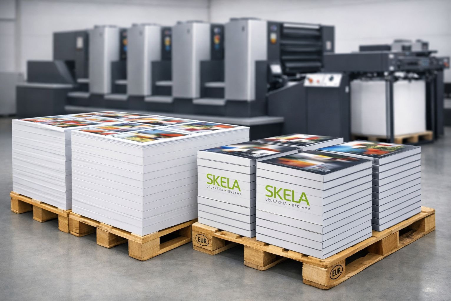 Stosy świeżo wydrukowanych materiałów reklamowych z logo firmy SKELA na paletach, w tle maszyna drukarska. Jasne oświetlenie, neutralne kolory.