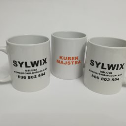 Seleo Druk - Trzy białe kubki z nadrukami: dwa z logo firmy remontowo-budowlanej 'Sylwix' i numerem telefonu, jeden z napisem 'Kubek Majstra' w pomarańczowej czcionce.