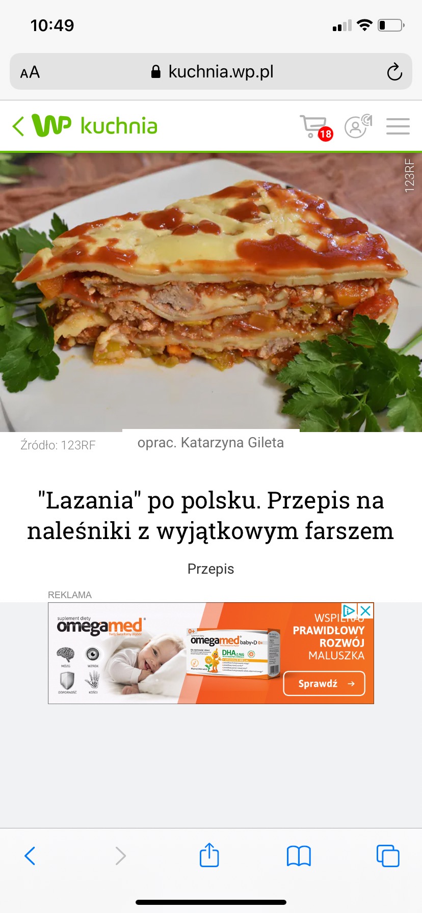 Przekrojony kawałek lasagne z naleśników, polany sosem pomidorowym, udekorowany zieloną pietruszką, na białym talerzu.