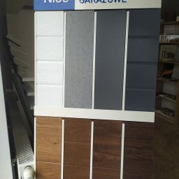 Stolar Agnieszka Pikulik - Ekspozycja próbek paneli do bram garażowych w różnych kolorach i fakturach, z logo producenta Nice widocznym u góry.