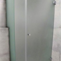 Usługi Szklarskie Bogusław Baj - Kabina prysznicowa z matowego szkła, z widocznymi chromowanymi zawiasami i minimalistycznym uchwytem, w łazience wykończonej szarą płytką.