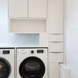 Biała zabudowa meblowa w pralni z pralką i suszarką Samsung, marmurowe płytki na ścianie.