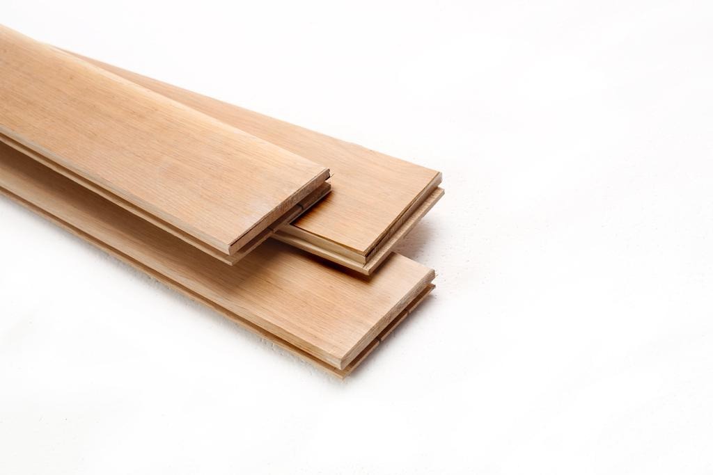 Trzy deski podłogowe z jasnego drewna, widoczne łączenia, ułożone na białym tle, prezentacja firmy z Dobrej.