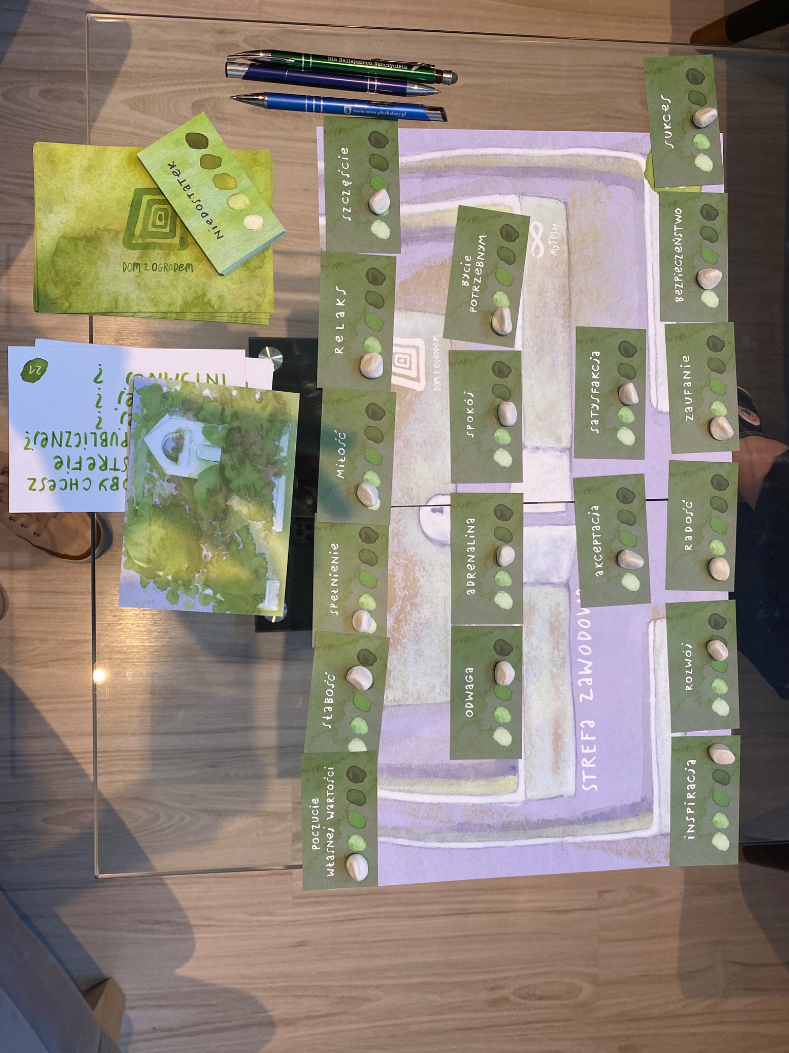 Plansza gry terapeutycznej z kartami 'Niedostatek', 'Szczęście', 'Relaks', 'Miłość', 'Spełnienie', 'Słabość', 'Poczucie własnej wartości', 'Odwaga', 'Adrenalina', 'Spokój', 'Bycie Potrzebnym'...