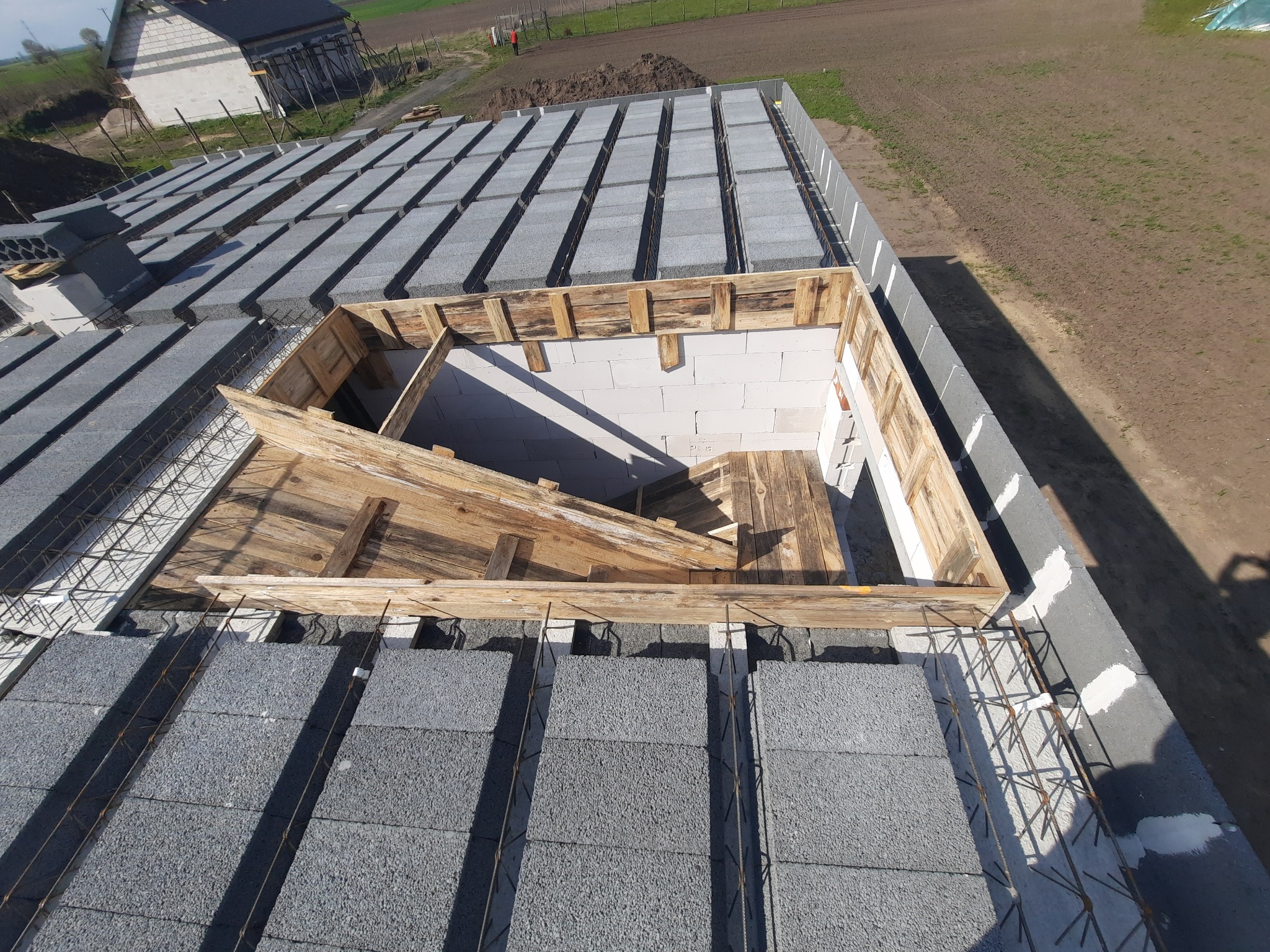 Budowa stropu Teriva z szalunkiem drewnianym, widok z góry na pustaki szare i zbrojenie.