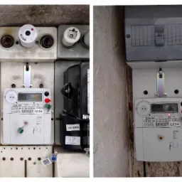 Dwa liczniki elektryczne zamontowane obok siebie w skrzynce, widoczne bezpieczniki topikowe, napisy na licznikach: CORAX1, G12w, PGE OZ, 4418570, P-1