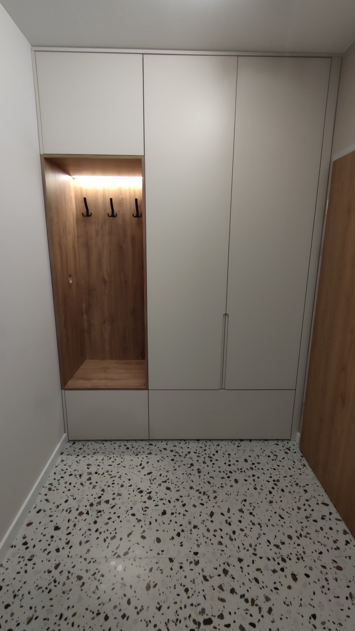 Jasna zabudowa przedpokoju z szafą i wnęką z wieszakami, oświetlona od góry, Bytom.