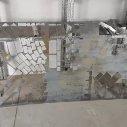 Metalowa płyta z wyciętymi wzorami geometrycznymi, leżąca w warsztacie, widoczne ślady obróbki i metalowe odpady na tle regałów.