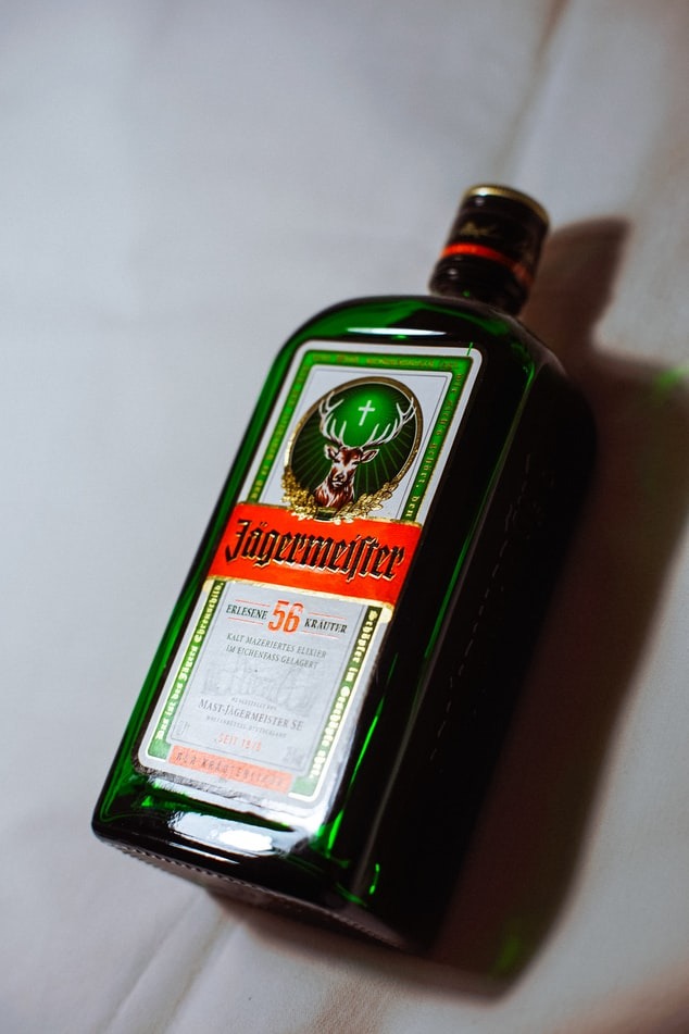 Butelka likieru ziołowego Jägermeister na białym tle, widoczne charakterystyczne logo z jeleniem i krzyżem.
