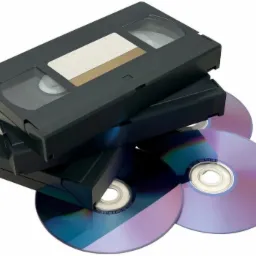 Stos kaset VHS i płyt DVD, gotowych do archiwizacji, na białym tle.