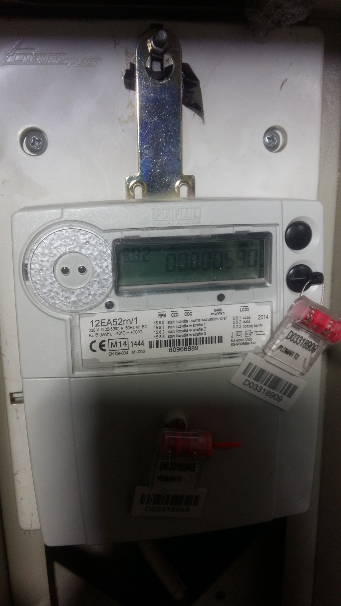 Zamknięty licznik energii elektrycznej marki PAFAL, z plombami zabezpieczającymi, zamontowany na białej plastikowej obudowie.