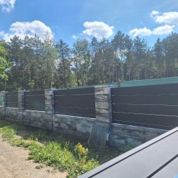 MTECH-POL Maciej Terlecki - Nowoczesne ogrodzenie z poziomych paneli w kolorze grafitowym, osadzone na kamiennej podmurówce i słupkach, z widoczną siatką maskującą w tle i fragmentem otwartej bramy wjazdowej z boku.