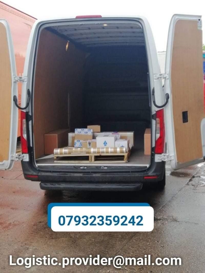 Wnętrze białego furgonetki z otwartymi drzwiami załadowane kartonami na palecie, widok z tyłu na mokrej nawierzchni.