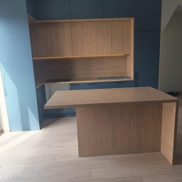 Meblebolo Przemysław Fuczyło - Nowoczesna kuchnia z wyspą: granatowe szafki górne i dolne, drewniane fronty szafek wiszących, oświetlenie LED pod szafkami, drewniana wyspa kuchenna.