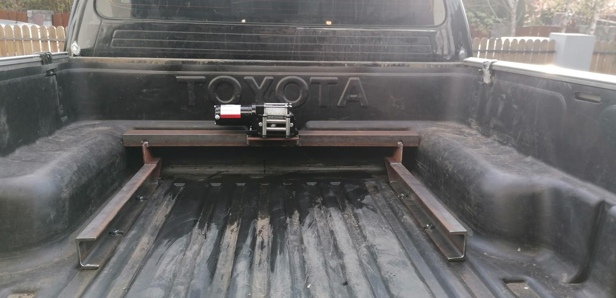Wciągarka zamontowana na spawanej, stalowej konstrukcji wewnątrz skrzyni ładunkowej samochodu Toyota.