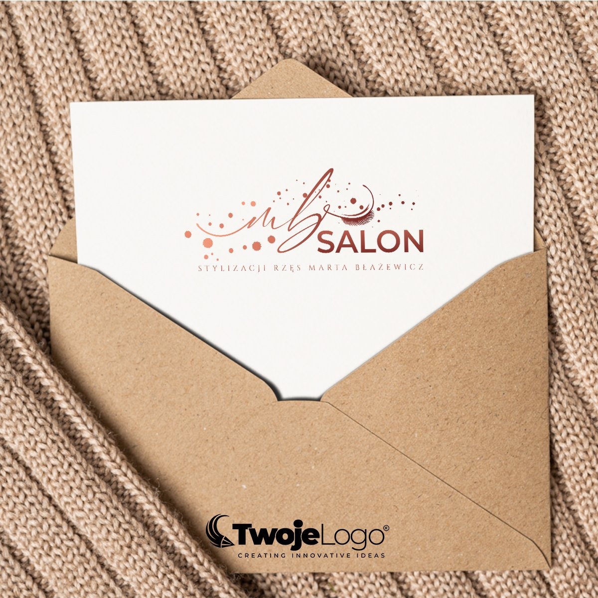 Wizytówka salonu stylizacji rzęs w brązowej kopercie na tle dzianiny. Logo salonu z delikatnymi zdobieniami i dopiskiem 'Stylizacji Rzęs Maria Błażewicz'.