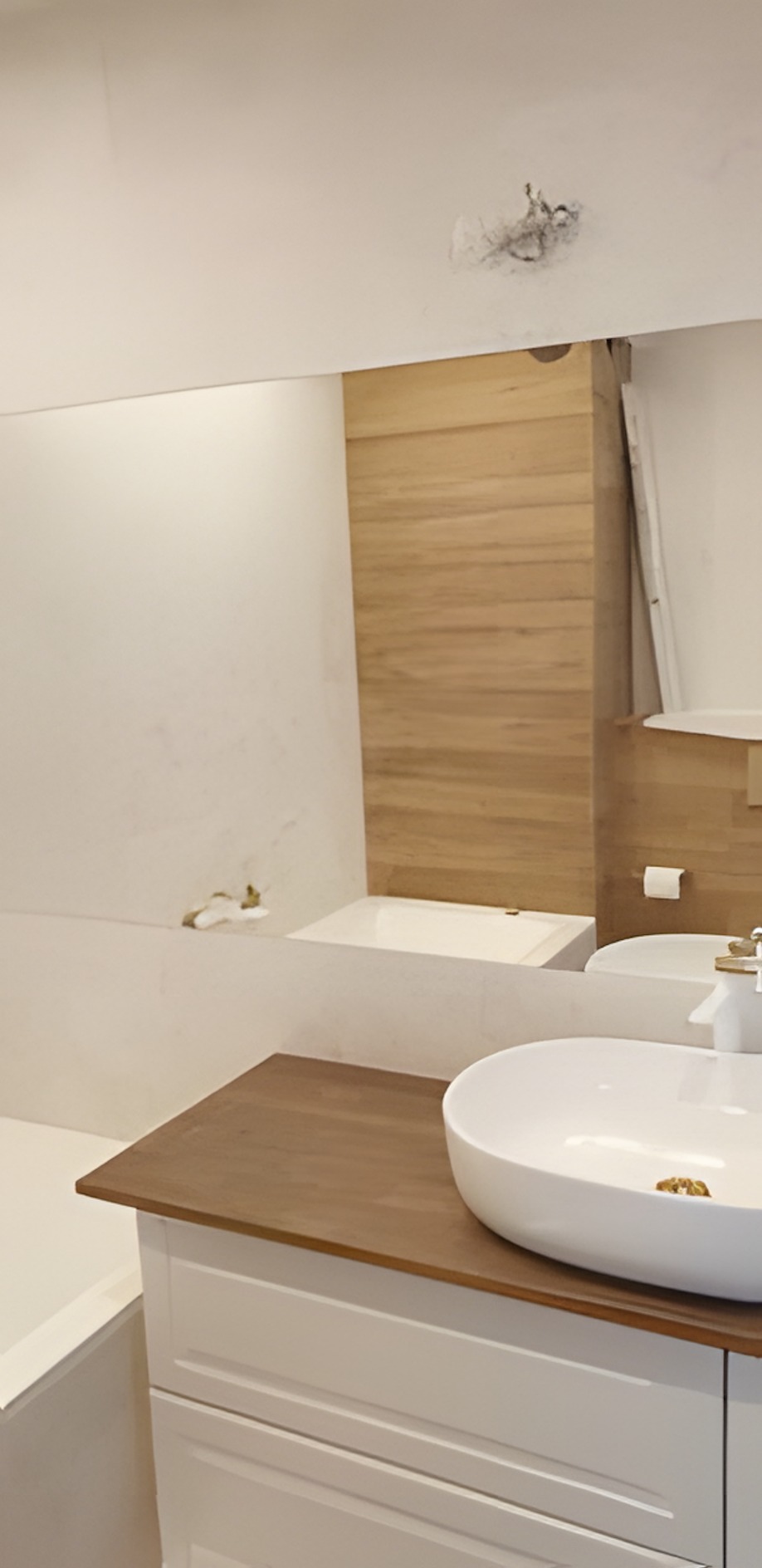 Nowoczesna łazienka z drewnianym akcentem: biała umywalka nablatowa na szafce, drewniana ściana i wanna w tle, odbicie lustra na suficie z plamą.