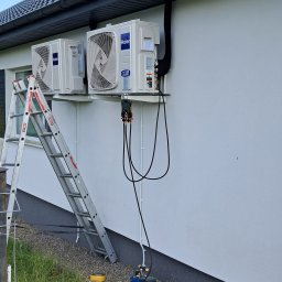 Szel Klima - Dwa klimatyzatory Haier zamontowane na elewacji domu. Widoczna drabina, przewody instalacyjne i narzędzia, co sugeruje etap montażu lub serwisu klimatyzacji.