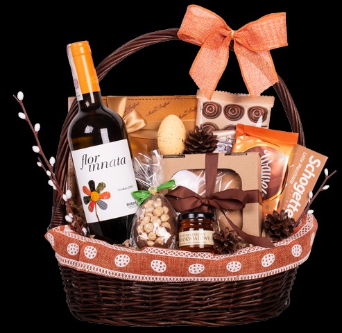 Wiklinowy kosz wypełniony winem Flor Innata, czekoladkami, miodem wielokwiatowym, orzechami w lukrze, ozdobiony pomarańczową kokardą i wstążką z motywem jajek.
