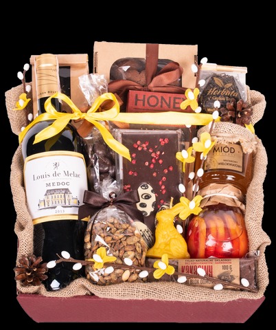 Elegancki kosz prezentowy z winem Medoc, miodem wielokwiatowym, czekoladą z różowym pieprzem, herbatą, orzechami w lukrze i świecą w kształcie zajączka, udekorowany jutą i żółtymi wstążkami.